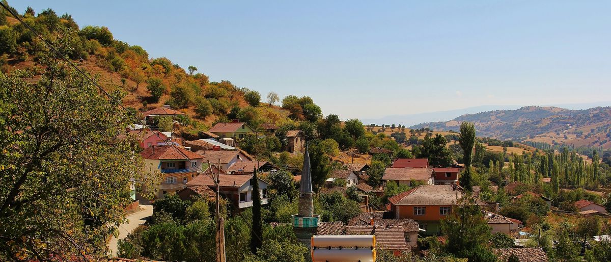Dorf mit roten Ziegeldächern und Minarett an einem Hang im anatolischen Hochland