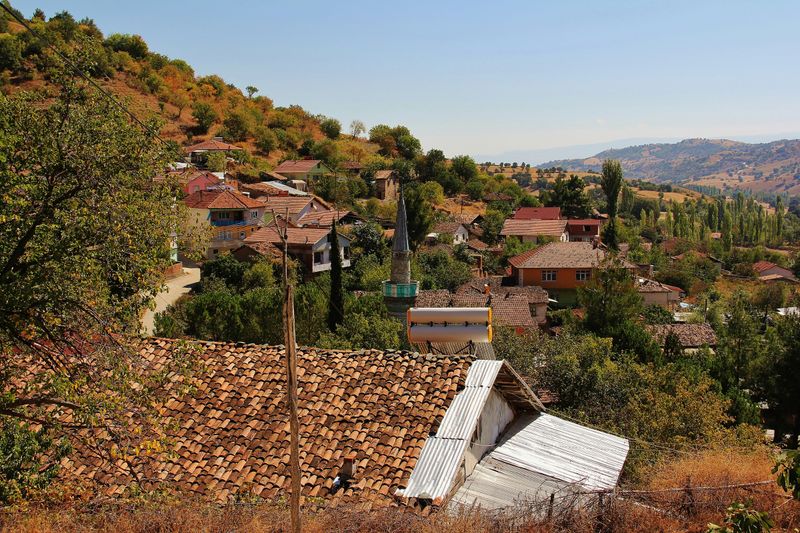 Dorf mit roten Ziegeldächern und Minarett an einem Hang im anatolischen Hochland