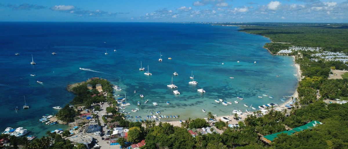 Luftaufnahme der Bucht von Bayahibe: Katamarane und Boote ankern im türkisblauen Wasser vor dem Ort und dem Strand