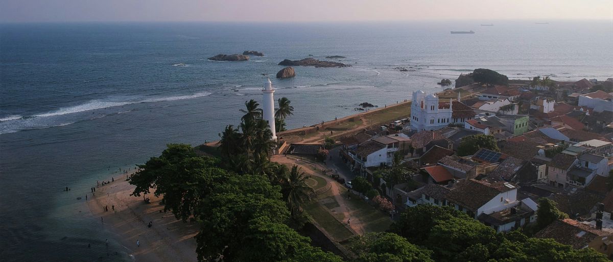 Luftbild der Festung von Galle: Leuchtturm, weiße Moschee und Ziegeldächer der Altstadt am Indischen Ozean, Abendlicht