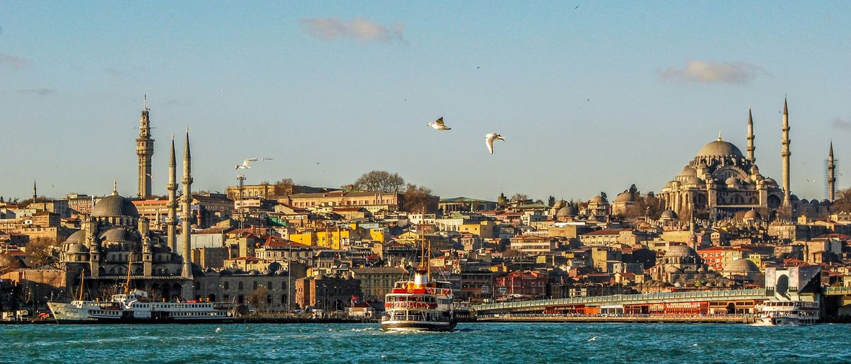 Blick über den Bosporus auf die Altstadt von Istanbul mit Moscheen und einer Fähre im Abendlicht