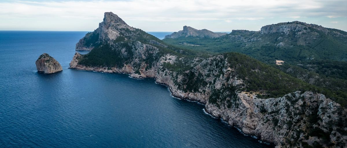 Felsinsel El Colomer vor der bewaldeten Halbinsel Formentor im Norden Mallorcas, davor tiefblaues Meer