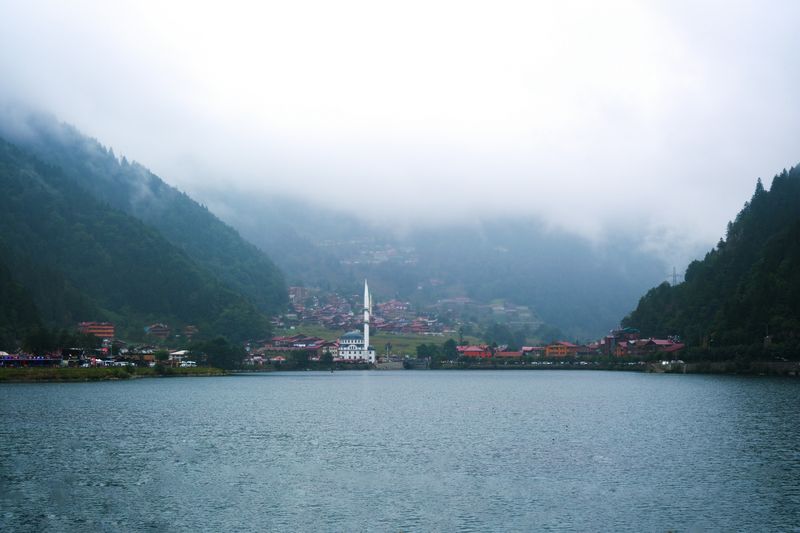 Uzungöl bei Trabzon: See zwischen bewaldeten Bergen, am Ufer der Ort mit Moschee, darüber Nebel